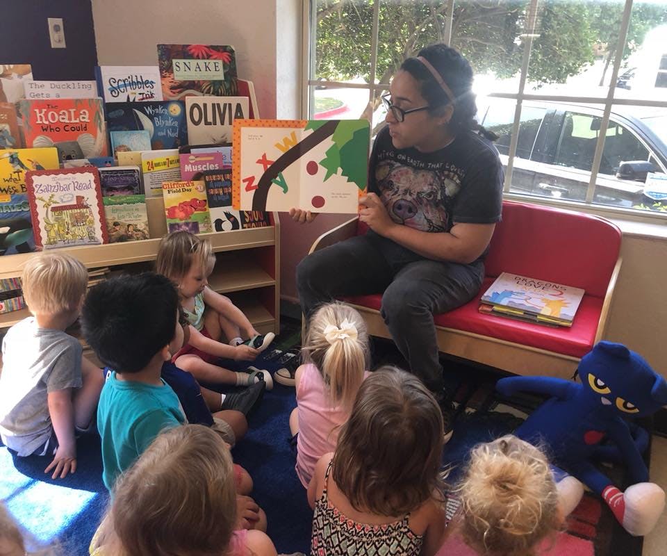 Person reading a book to a group of children in a classroom