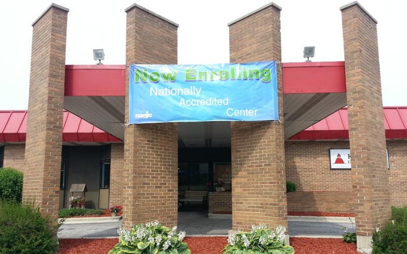 A blue banner hangs between two brick pillars that reads "Now Enrolling Nationally Accredited Center"