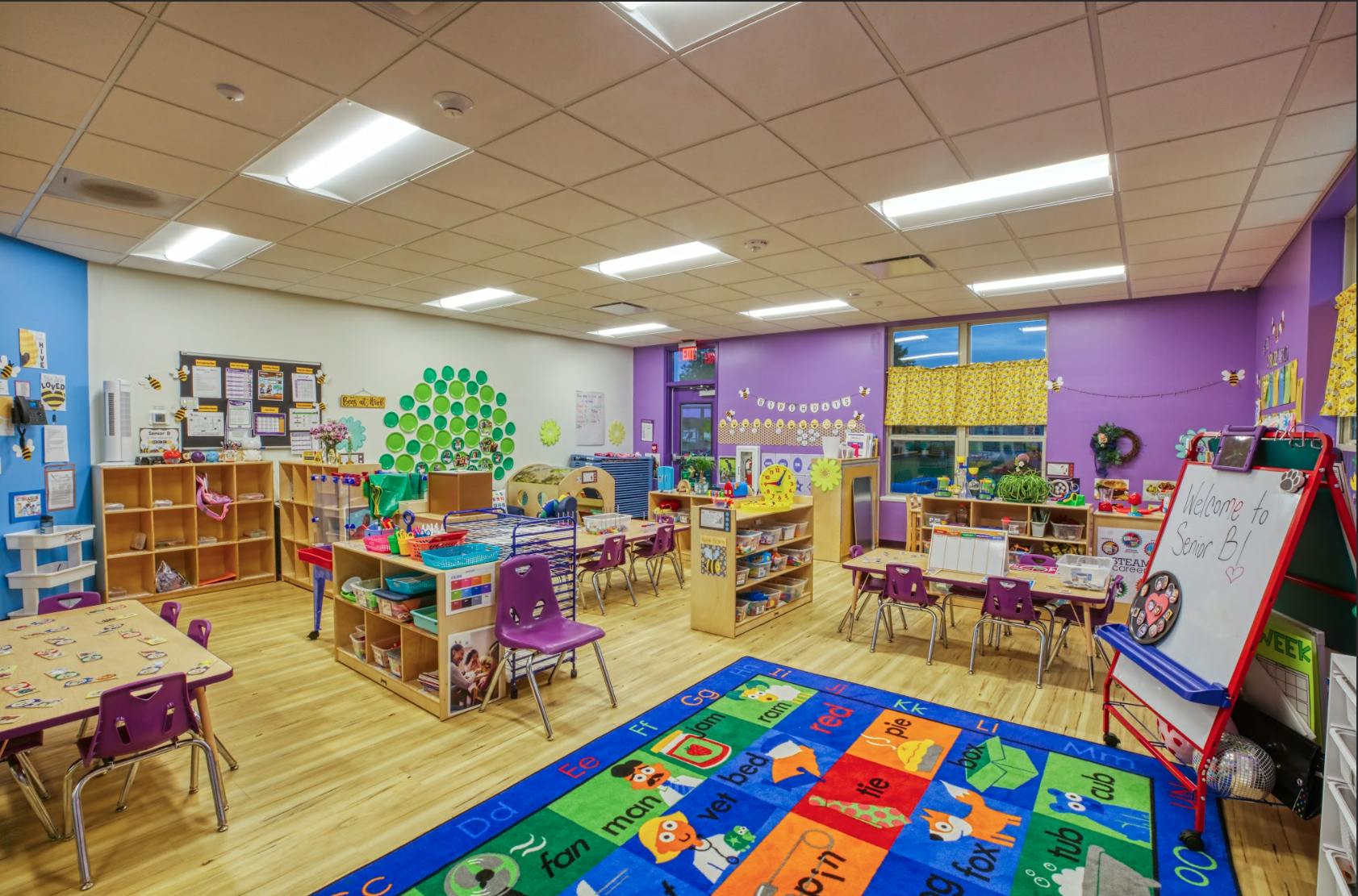 Empty classroom with small tables, chairs, and colorful rug