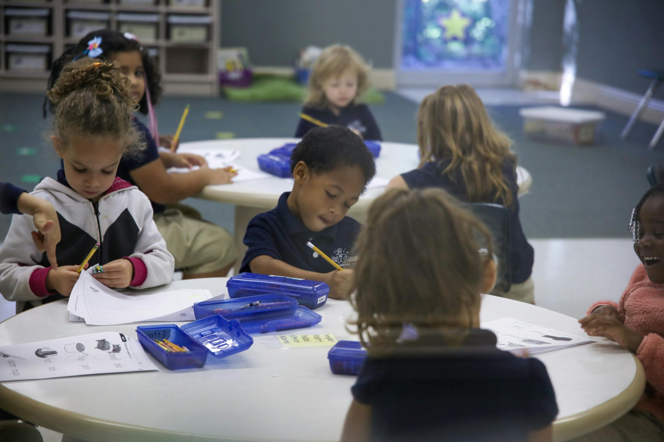 Children sitting at tables and writing in a classroom