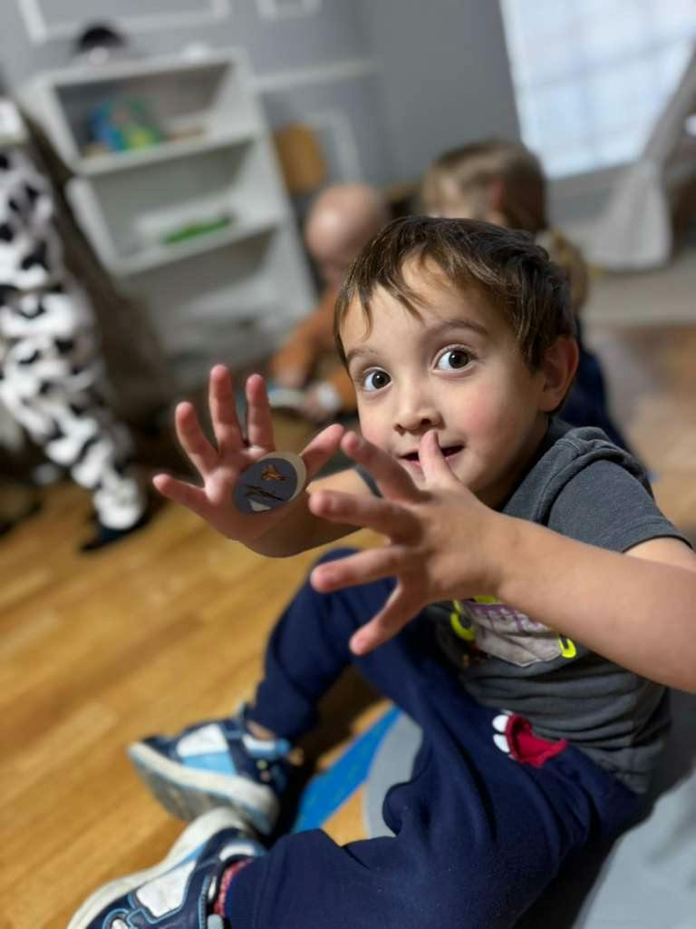 Child sitting on floor showing a small circular sticker on their palm