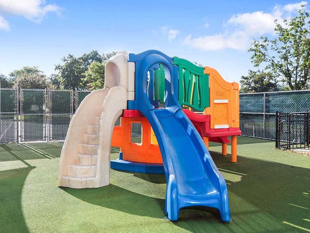 Colorful plastic playground slide and climbing structure on artificial turf