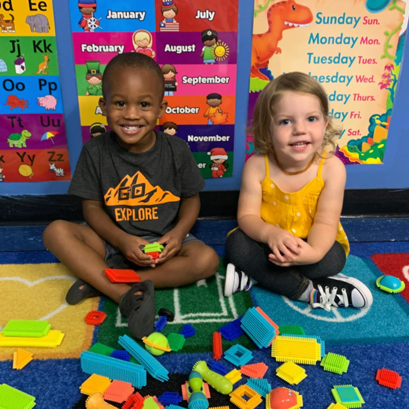Two children sitting on a rug with colorful building blocks