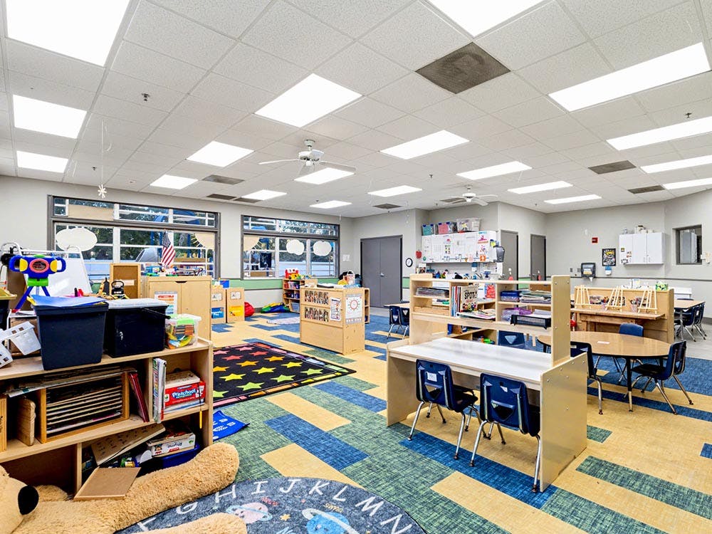 Empty classroom with colorful carpet and small tables and chairs