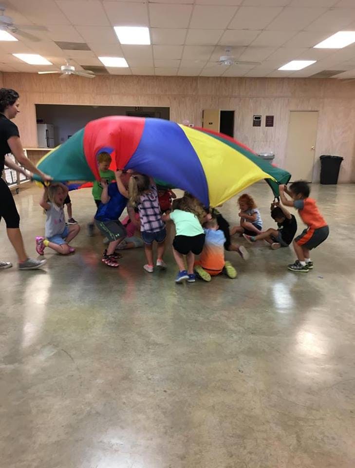 Children playing with a colorful parachute indoors