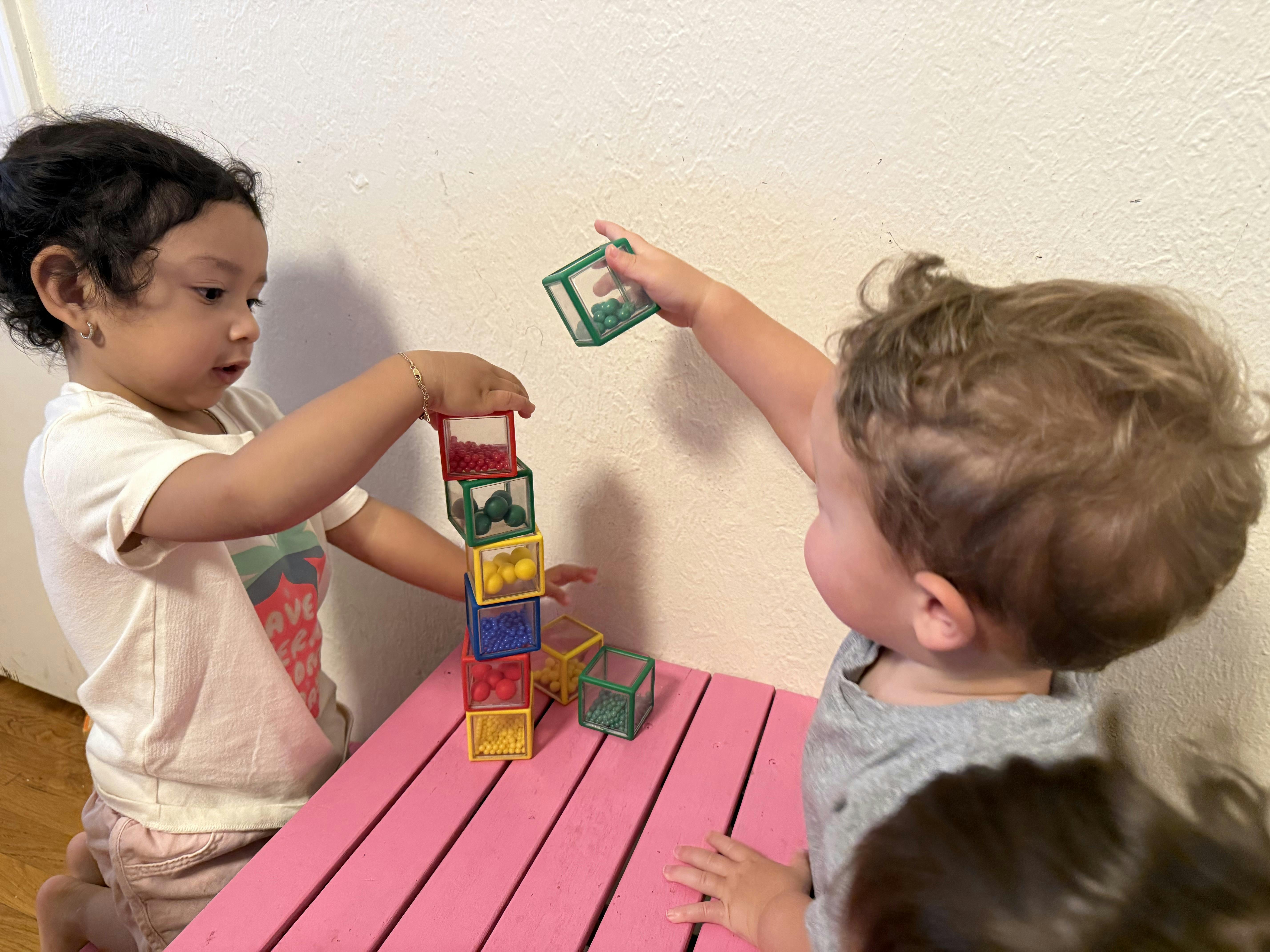 Two children playing with colorful clear blocks filled with small beads