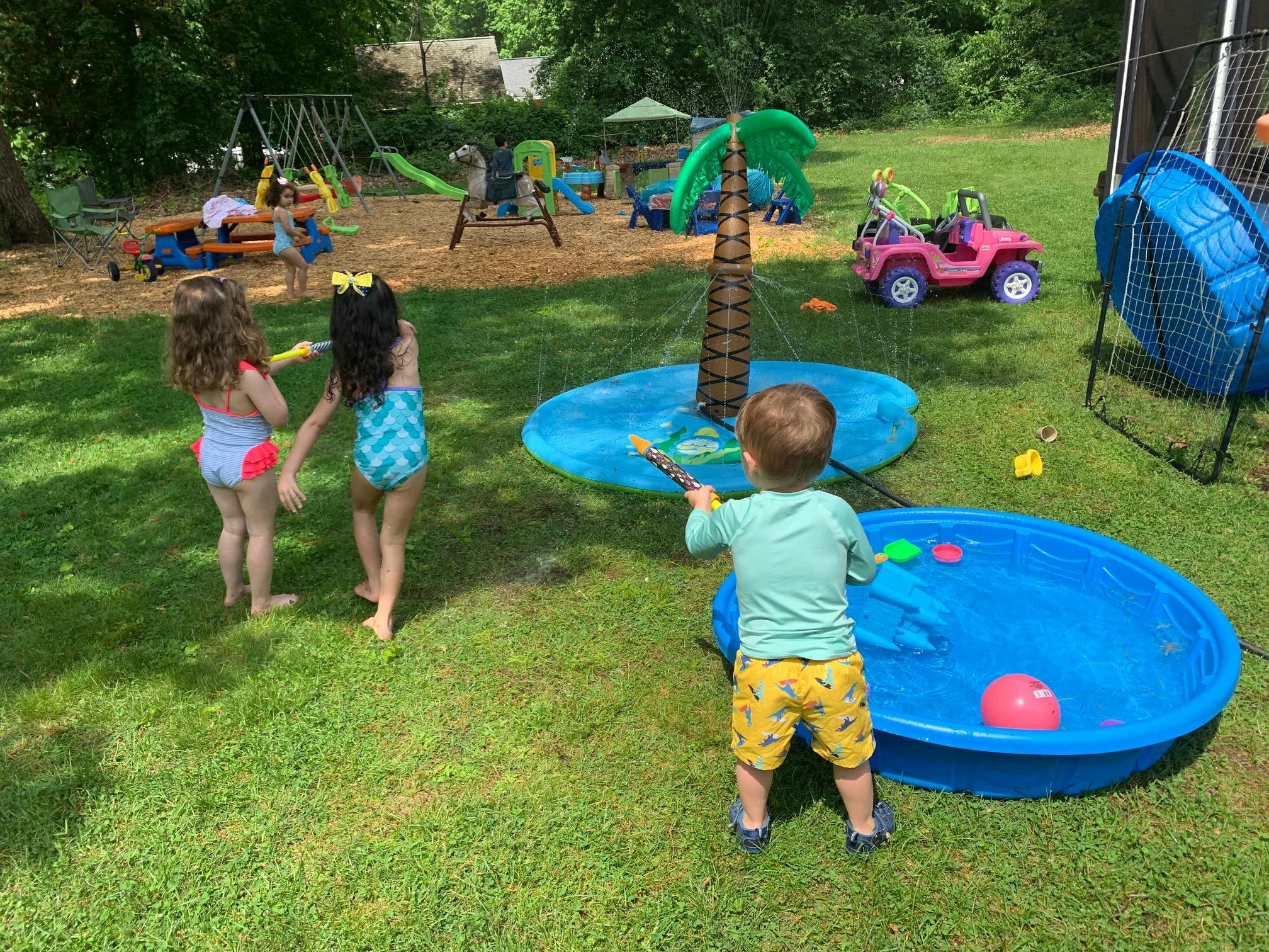 Children playing with water toys in a grassy yard