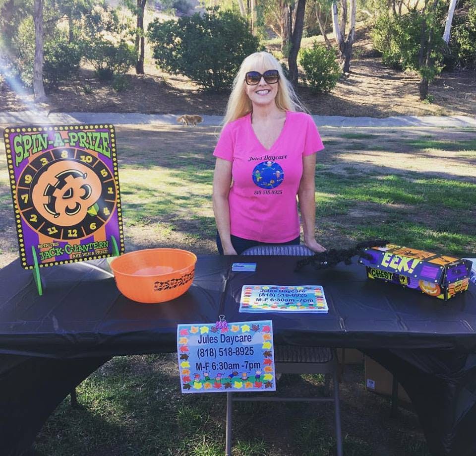 Person standing behind a table with a "Spin a Prize" game and an orange bowl