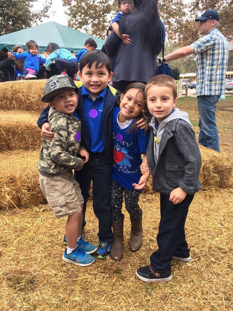 Four children standing together in front of hay bales