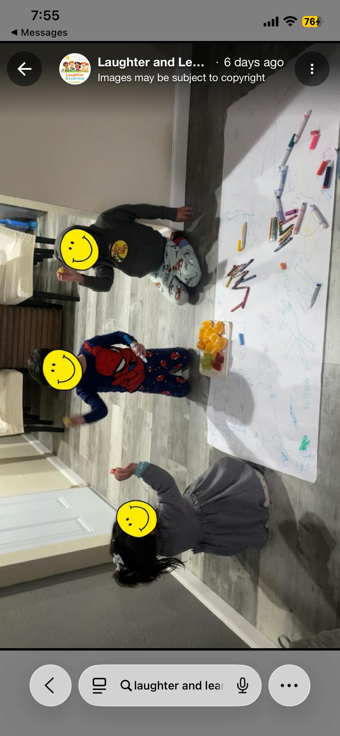 Three children drawing on a large sheet of paper on the floor