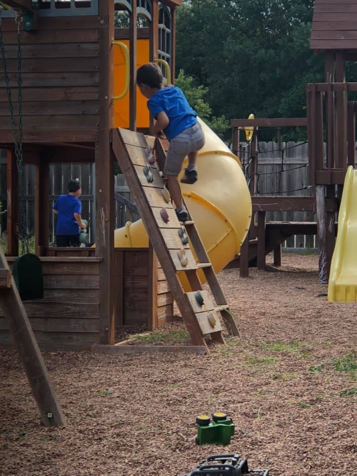 Child climbing a rock wall on a playground structure
