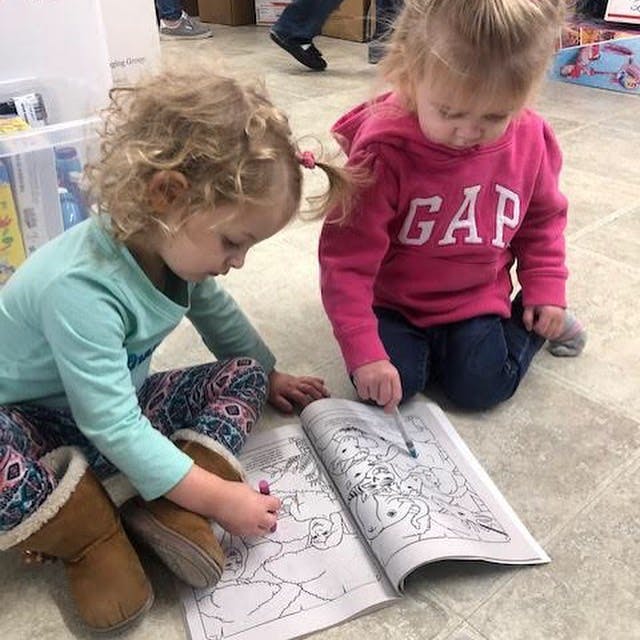 Two children coloring in a book on the floor
