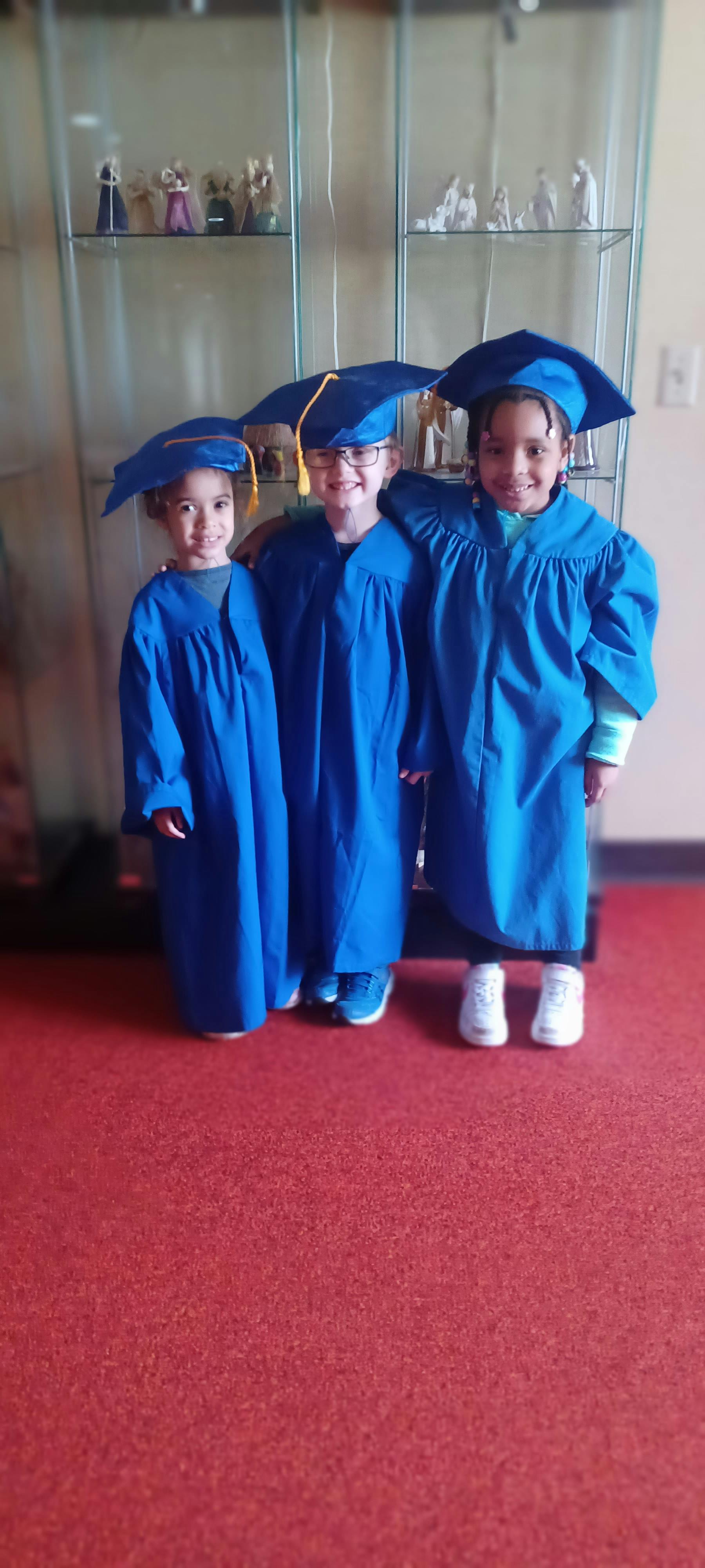 Three children in blue graduation caps and gowns