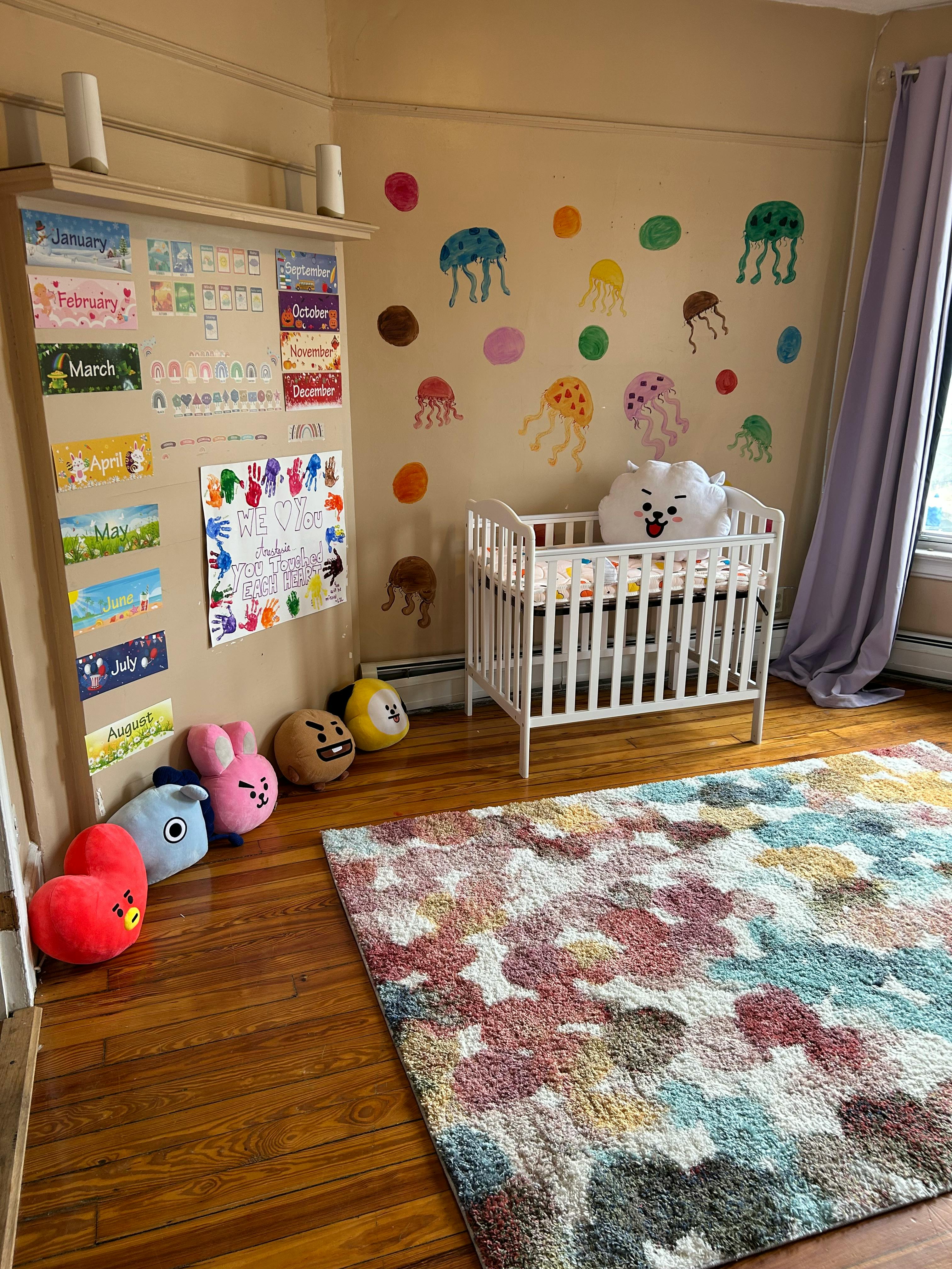 Nursery room with a white crib, colorful rug, and wall decorations
