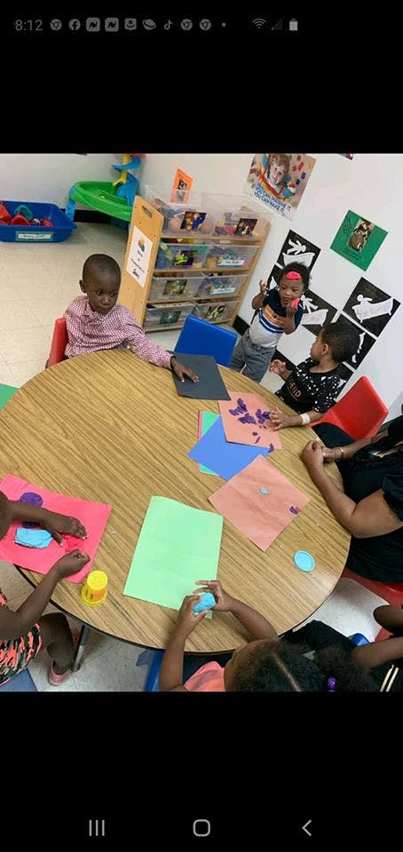 Children doing crafts at a round table in a classroom