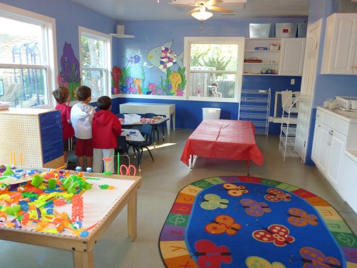 Three children standing at a table in a classroom