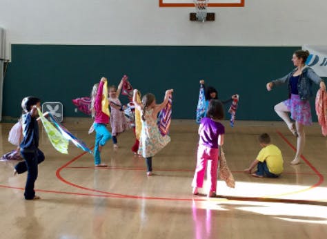 Adult and children dancing with colorful scarves in a gym