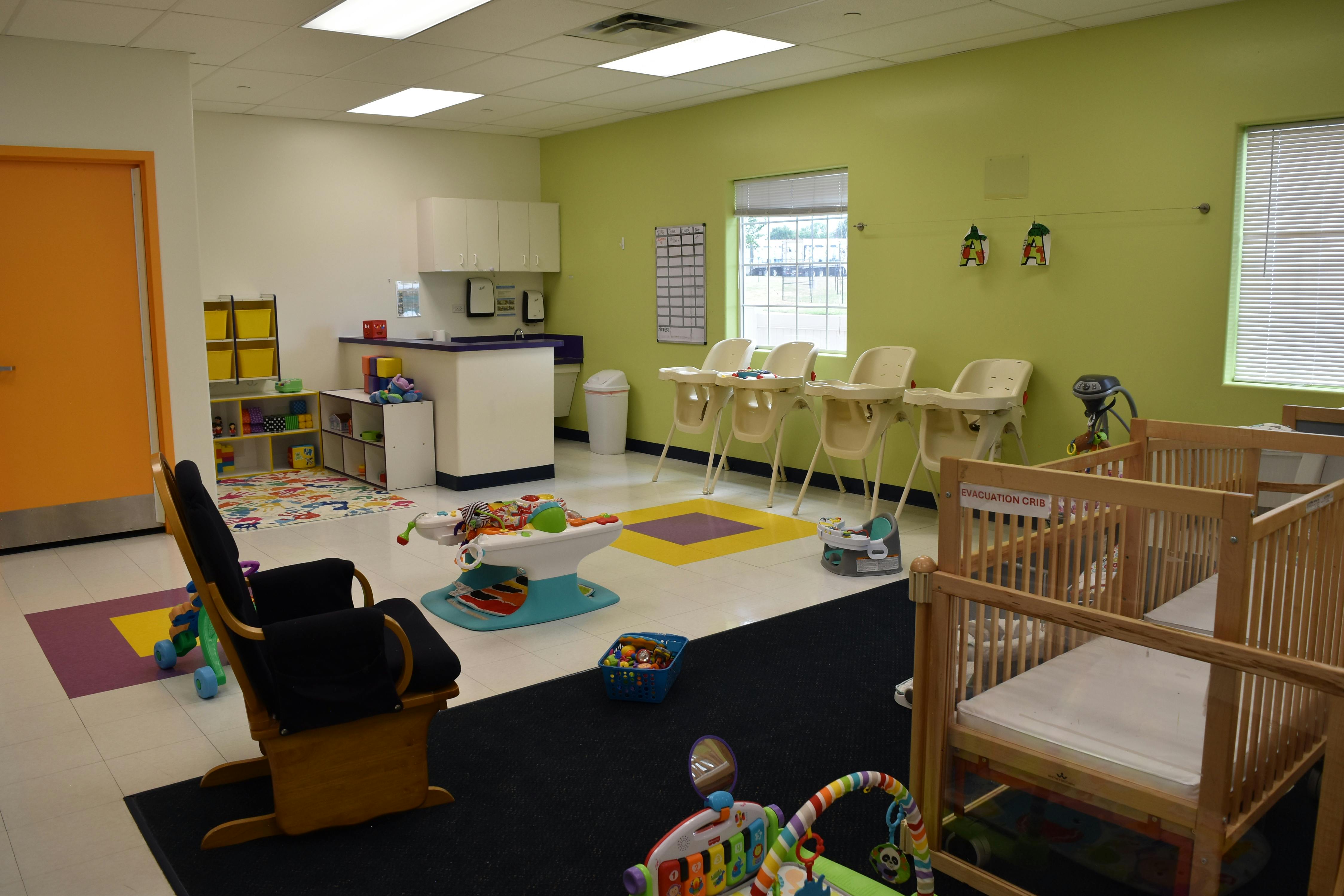 Daycare room with cribs, high chairs, and play mats
