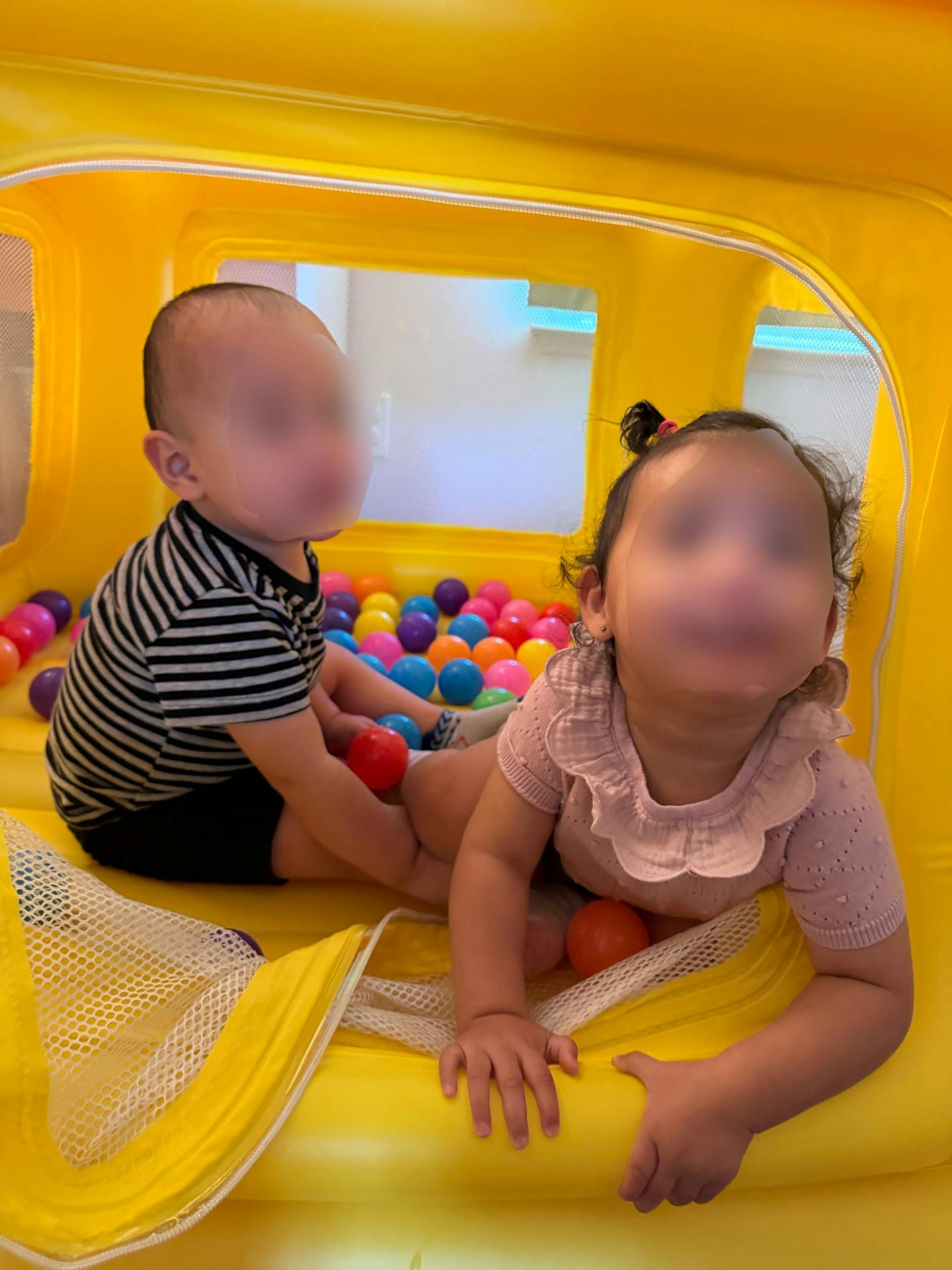 Two children playing in a yellow ball pit