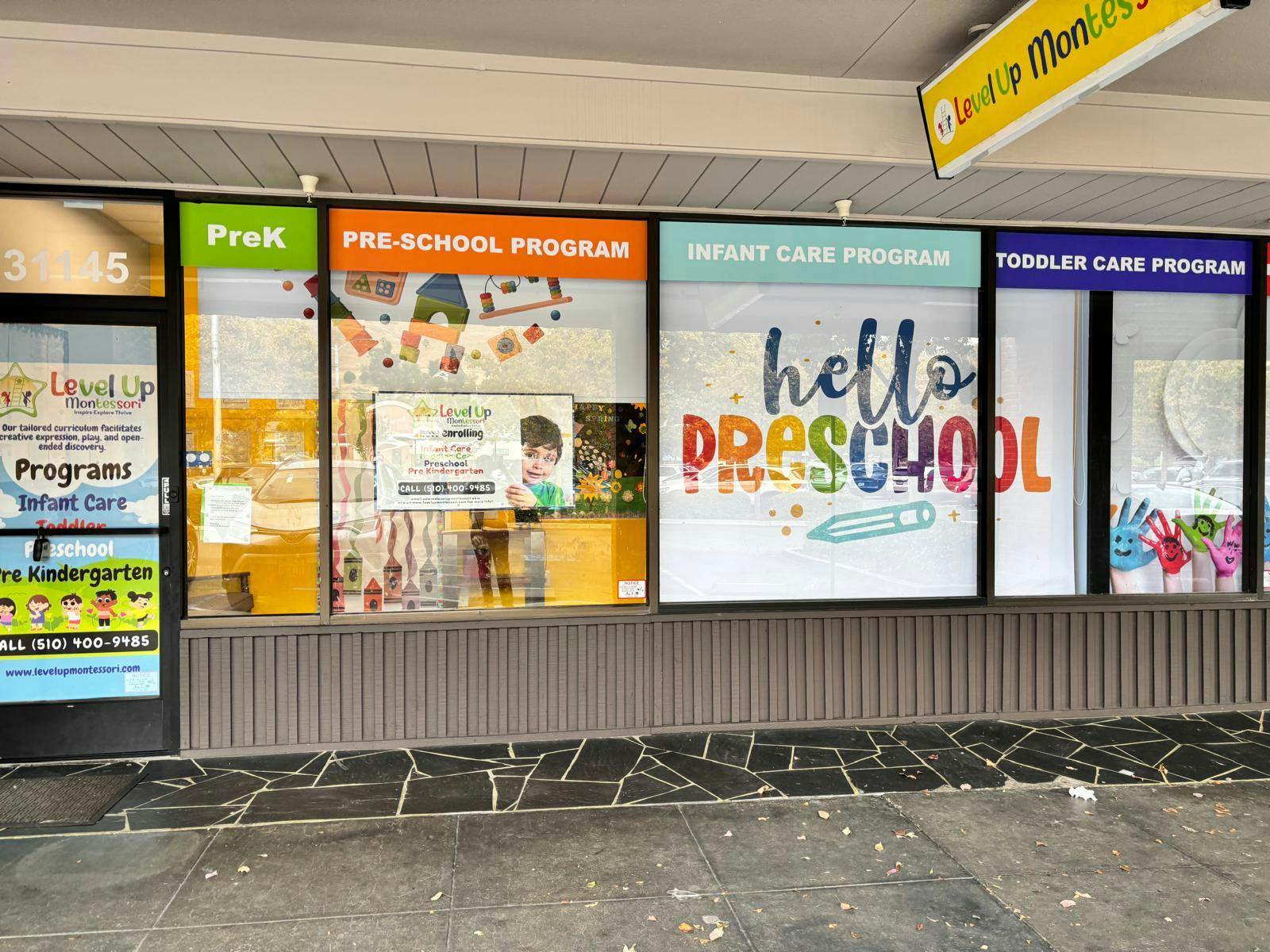 Storefront windows of a preschool with signs for different programs
