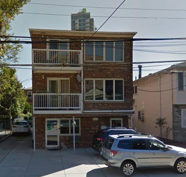 Brick building with balconies and parked cars