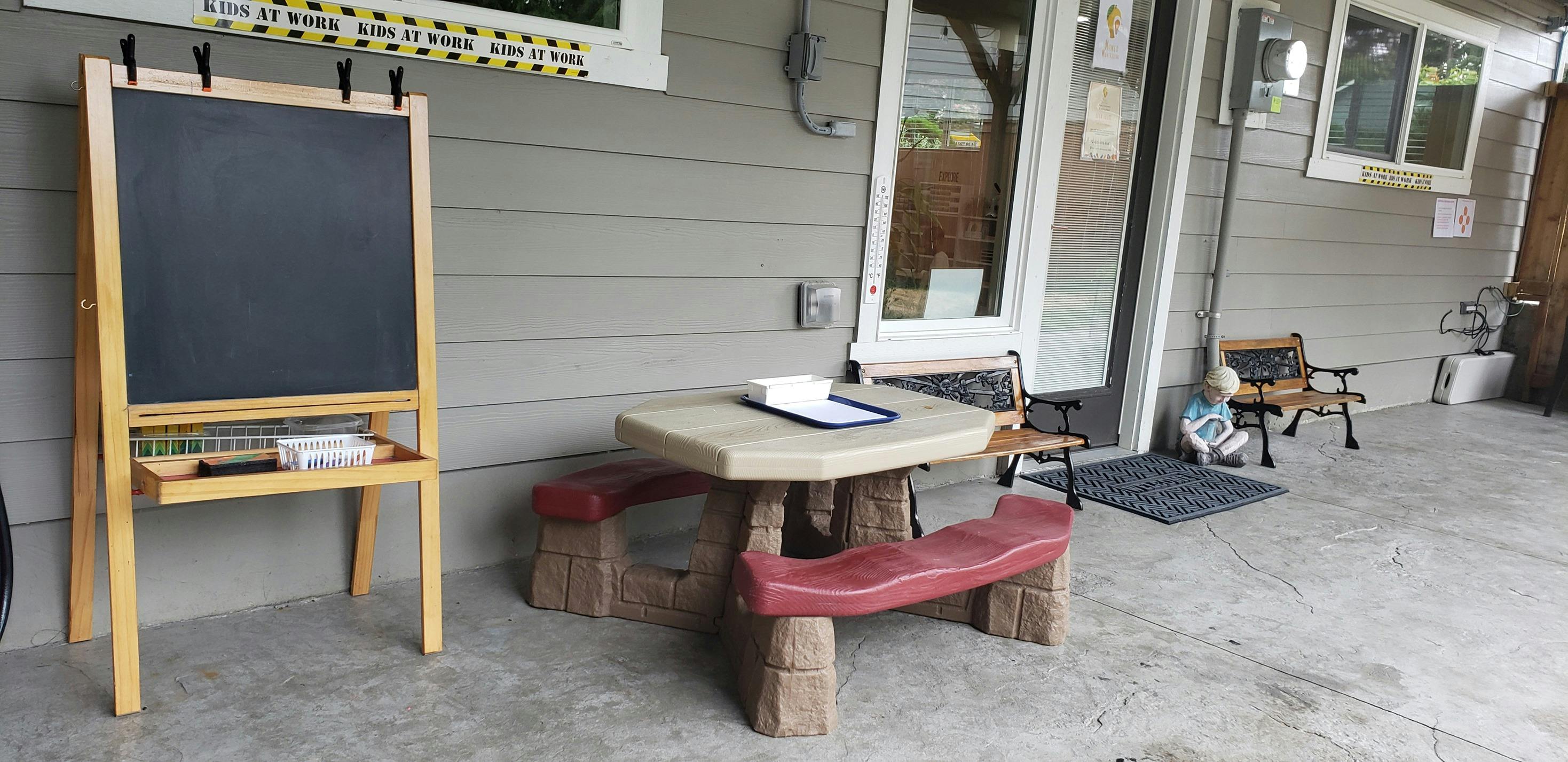 Chalkboard easel and child-sized picnic table on a patio