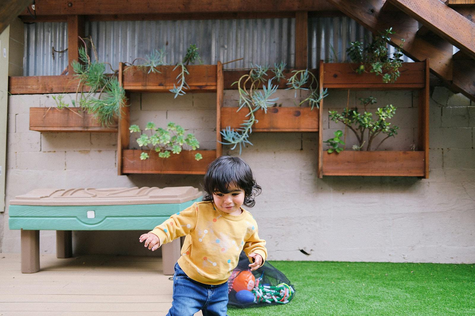 Child standing on a deck in a backyard