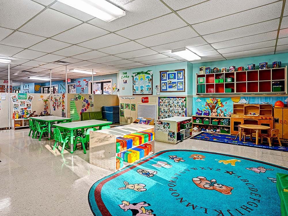Classroom with child-sized tables and chairs, cubbies, and a colorful rug