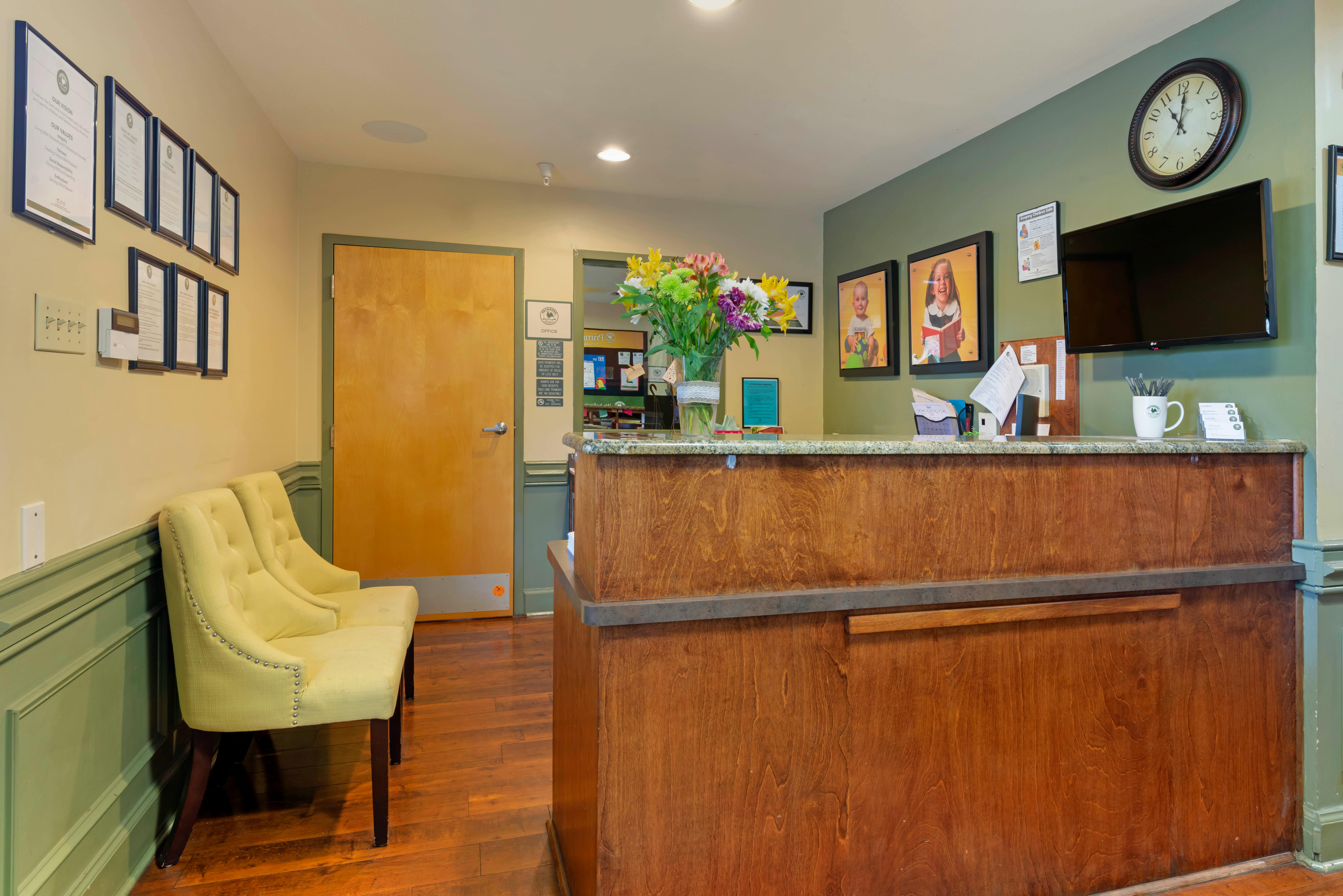 waiting room with a wooden reception desk and two light yellow chairs