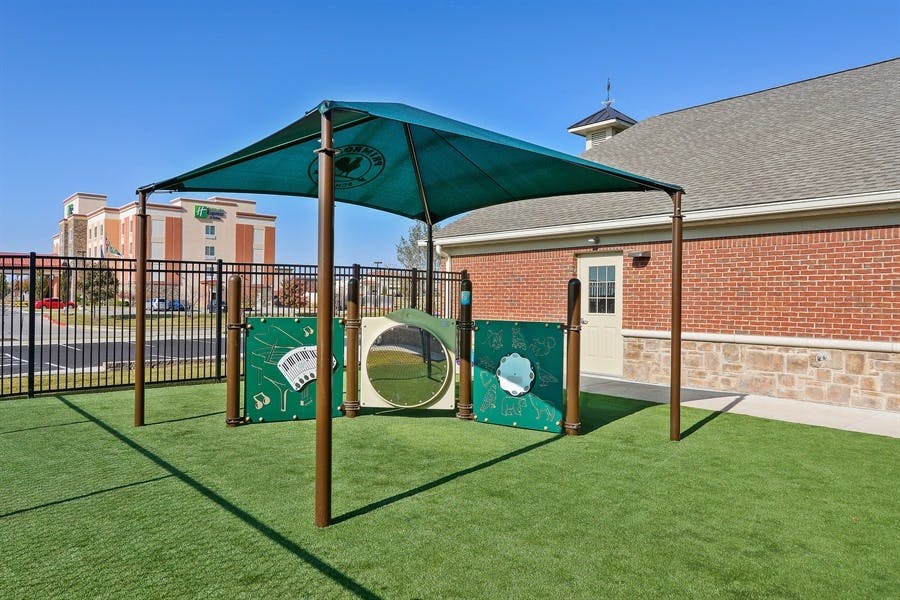Outdoor play area with green turf and a shaded structure