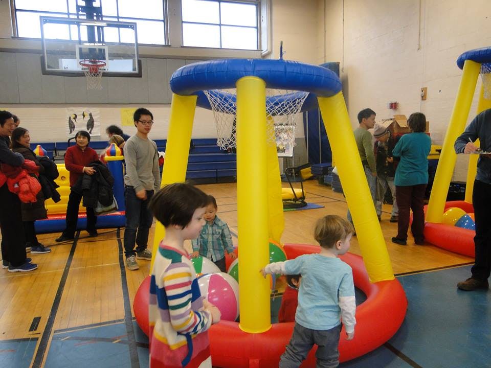 Children playing with inflatable basketball hoops in a gymnasium