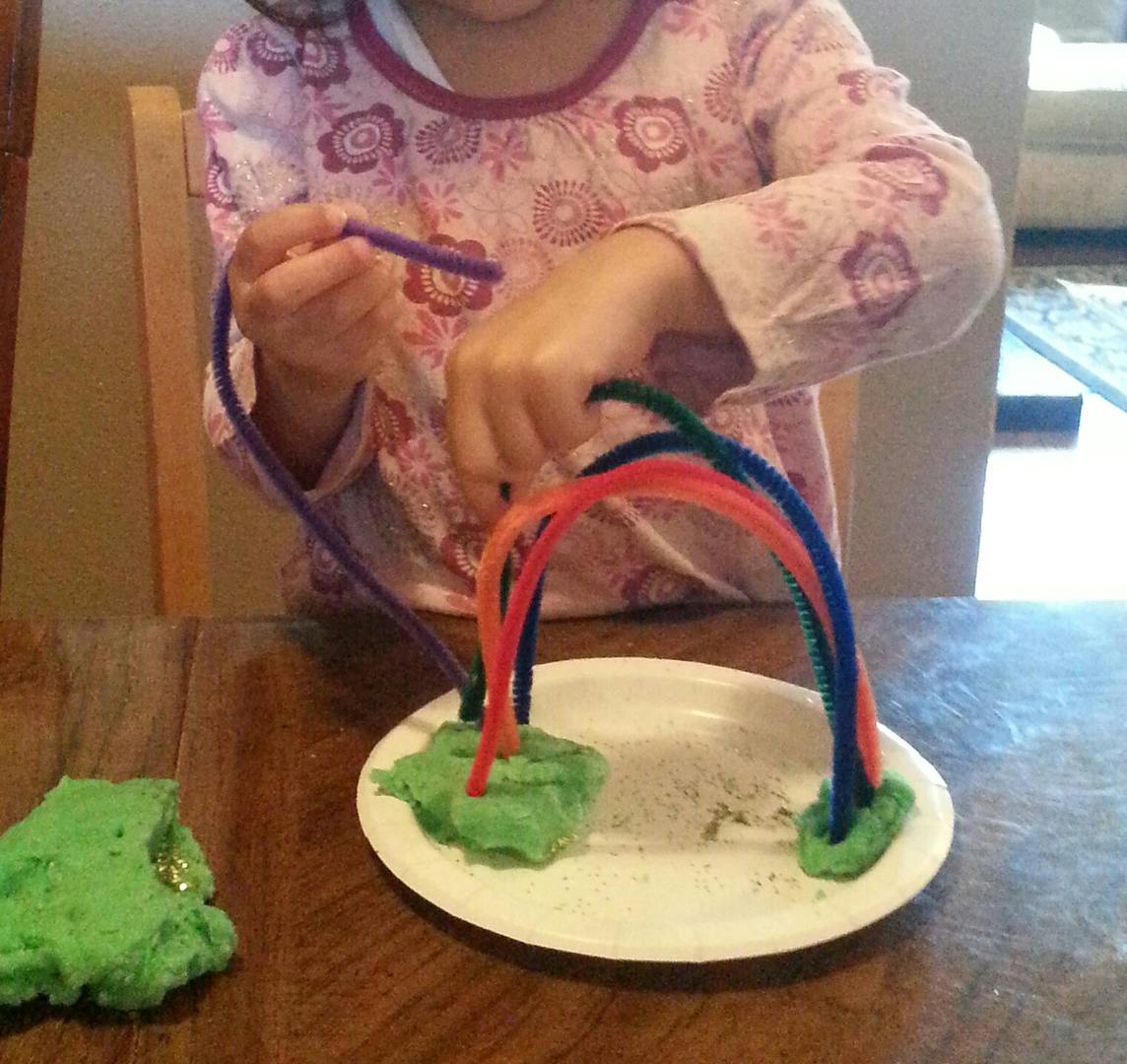 Child making a craft with pipe cleaners and green playdough