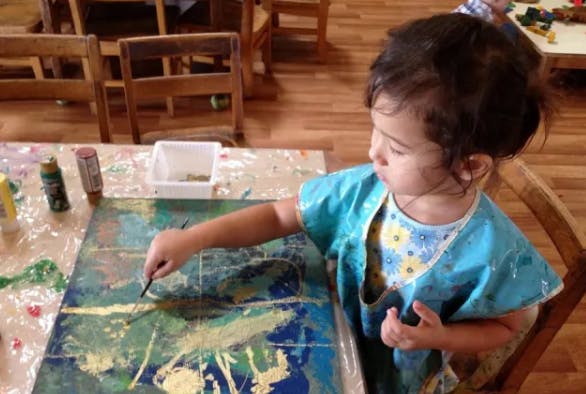 Child painting on a canvas in a classroom