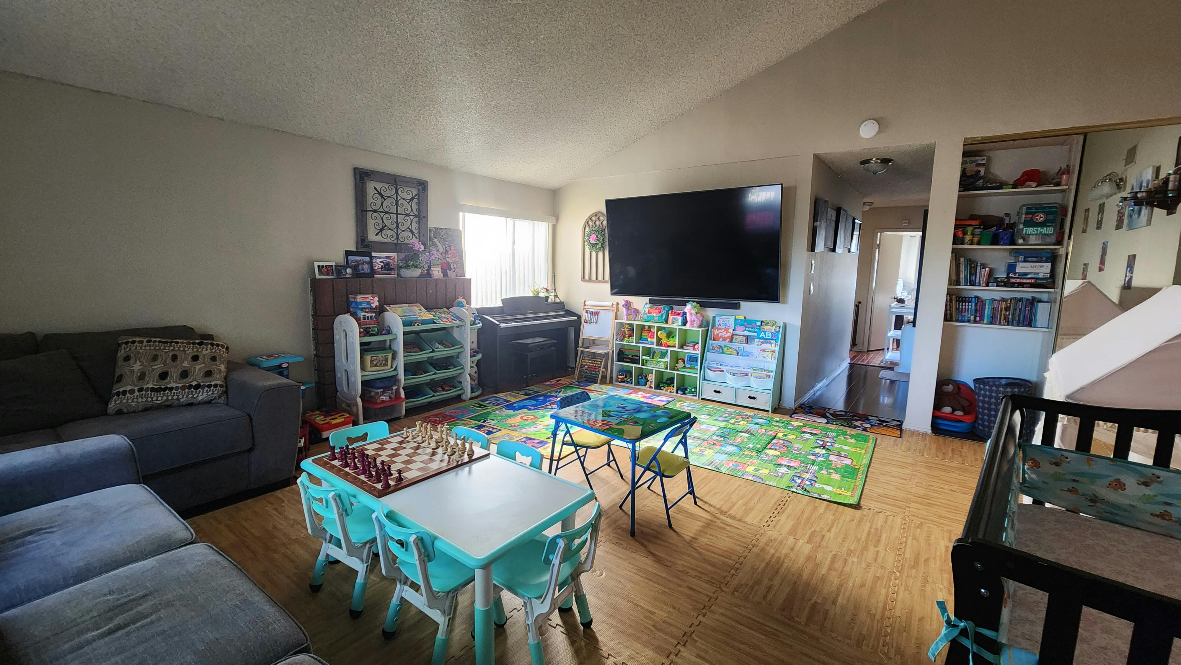 Living room with a sofa, small tables and chairs, and a crib