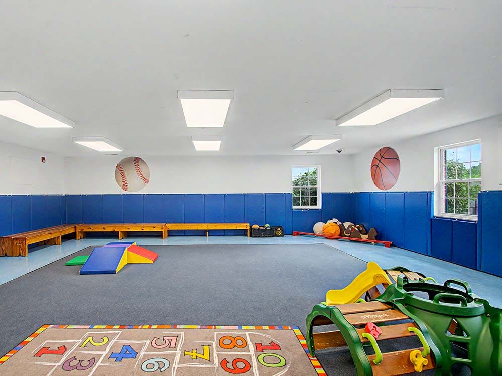 Indoor play area with blue wall padding and various colorful play equipment