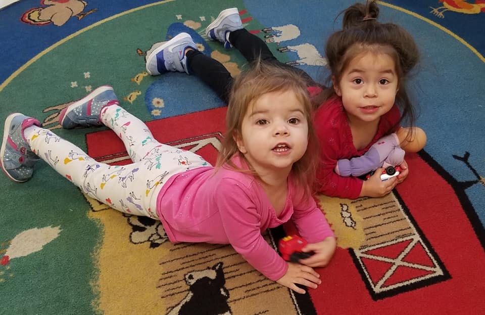 Two children lying on a colorful rug