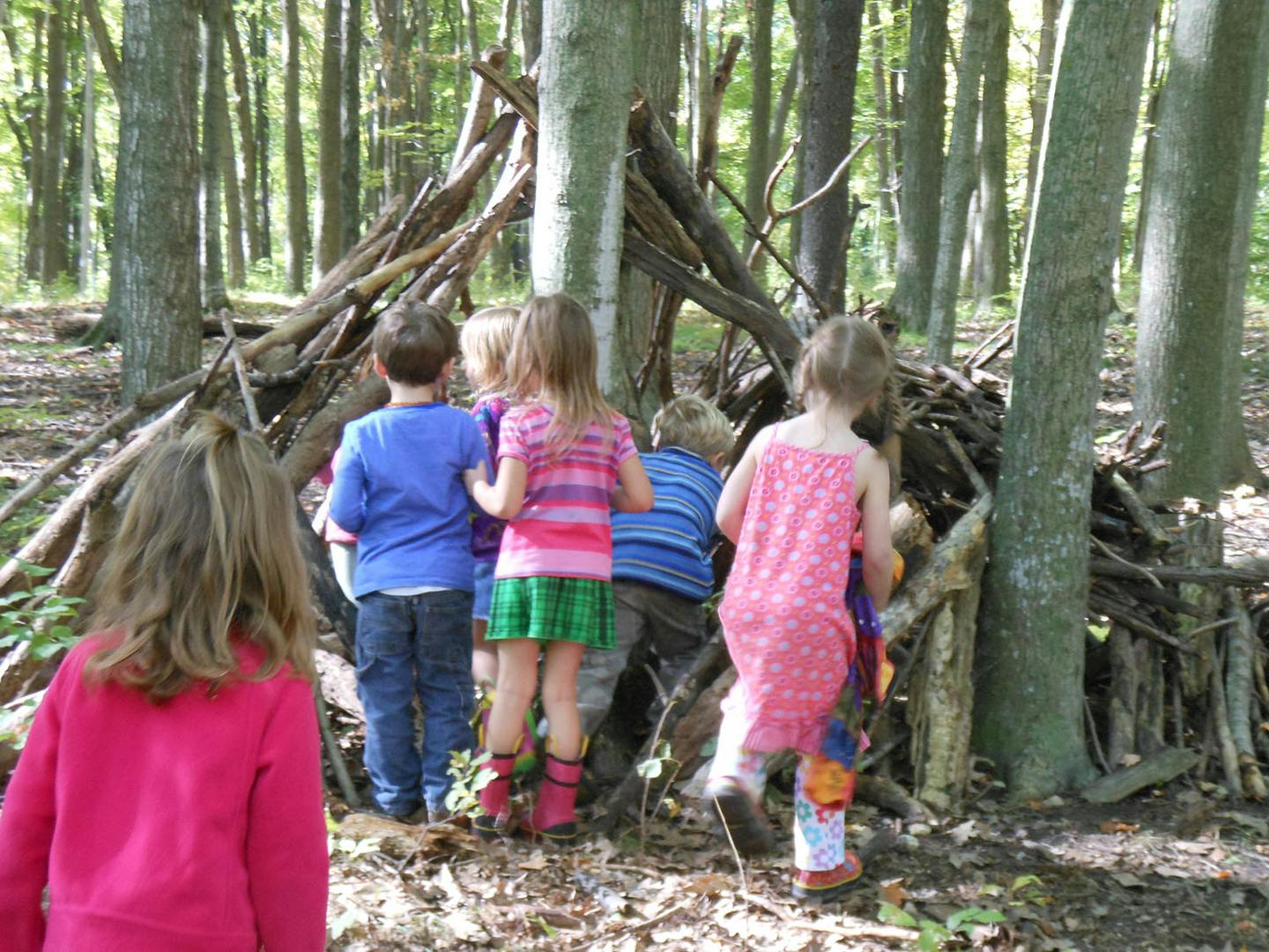 Children playing in a stick fort in the woods
