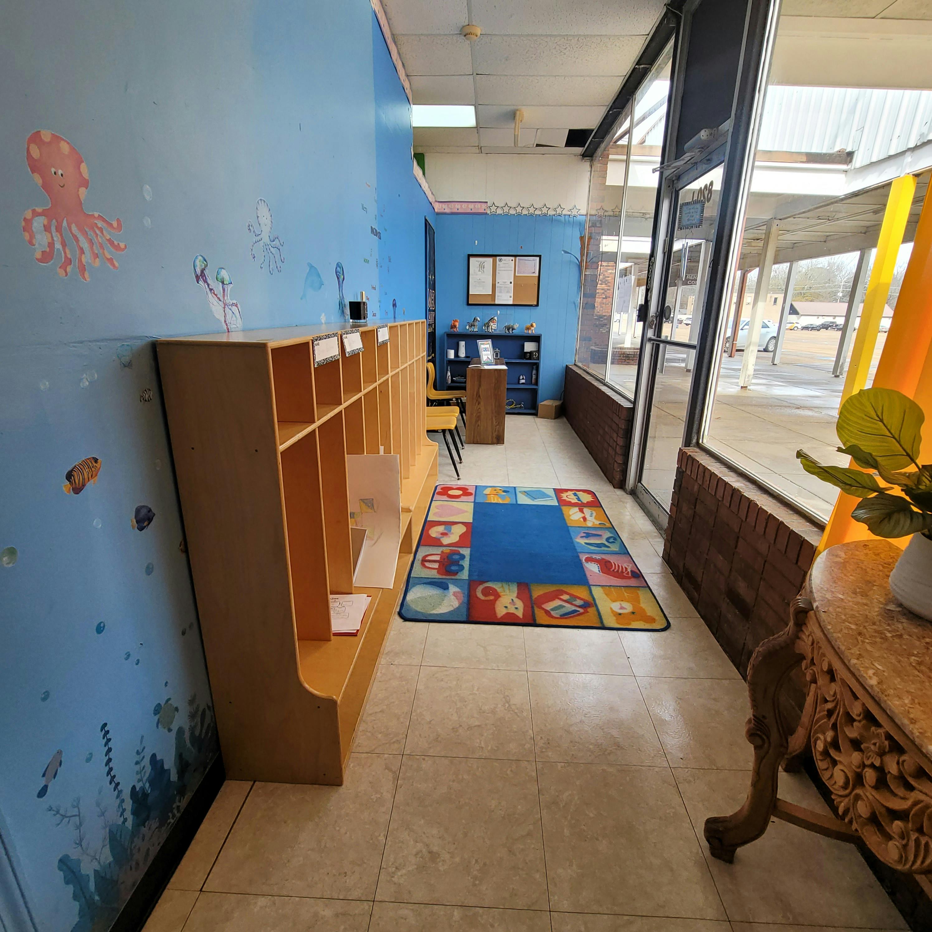 Classroom with cubbies, blue wall with sea creatures, and a colorful rug