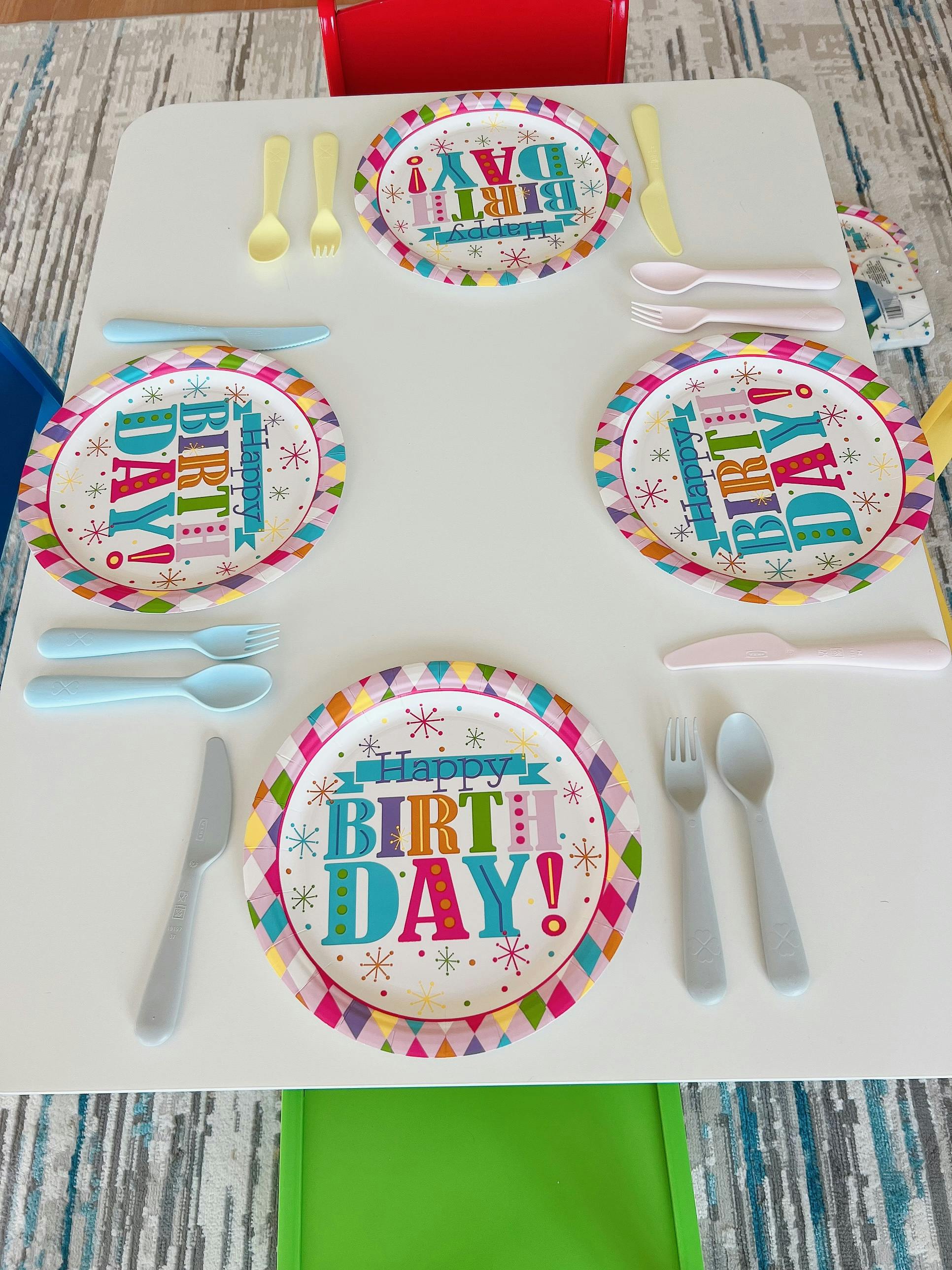 Table set with "Happy Birthday" paper plates and plastic cutlery