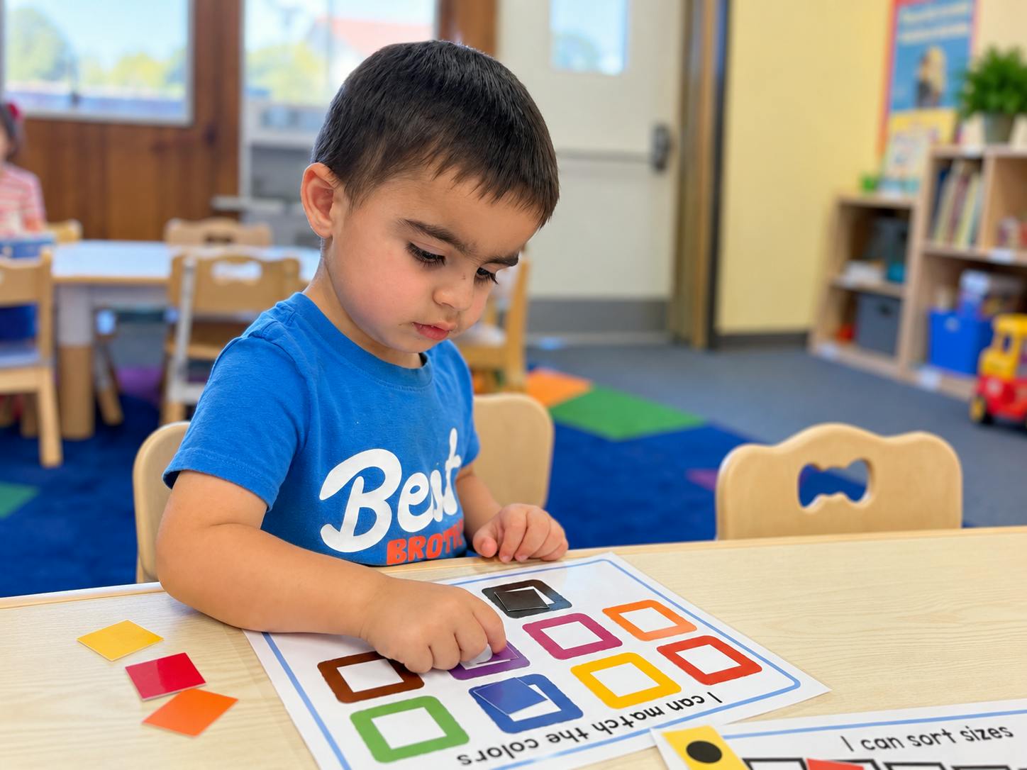 Child matching colored shapes on a worksheet in a classroom