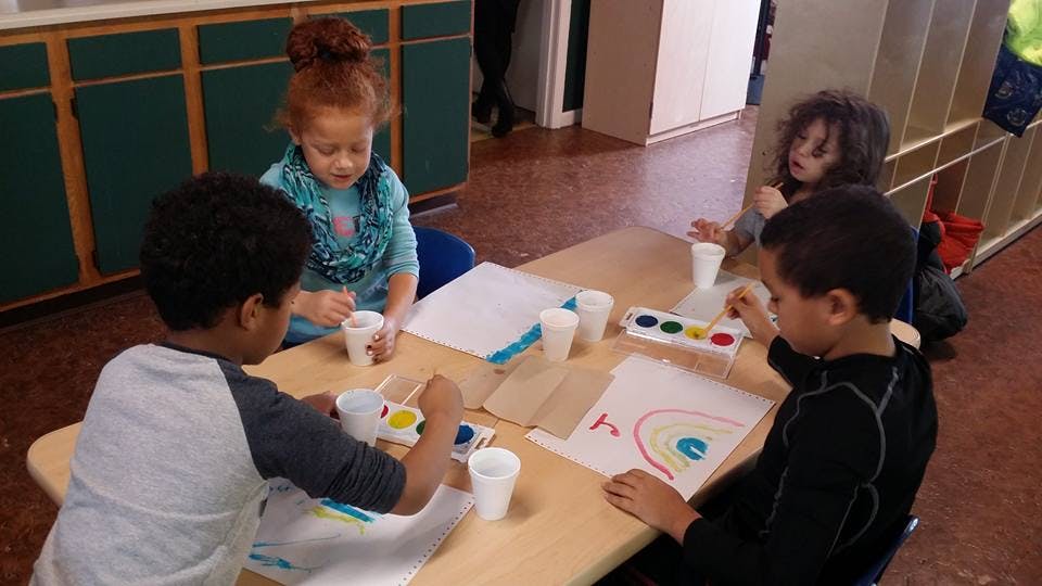 Four children painting at a table