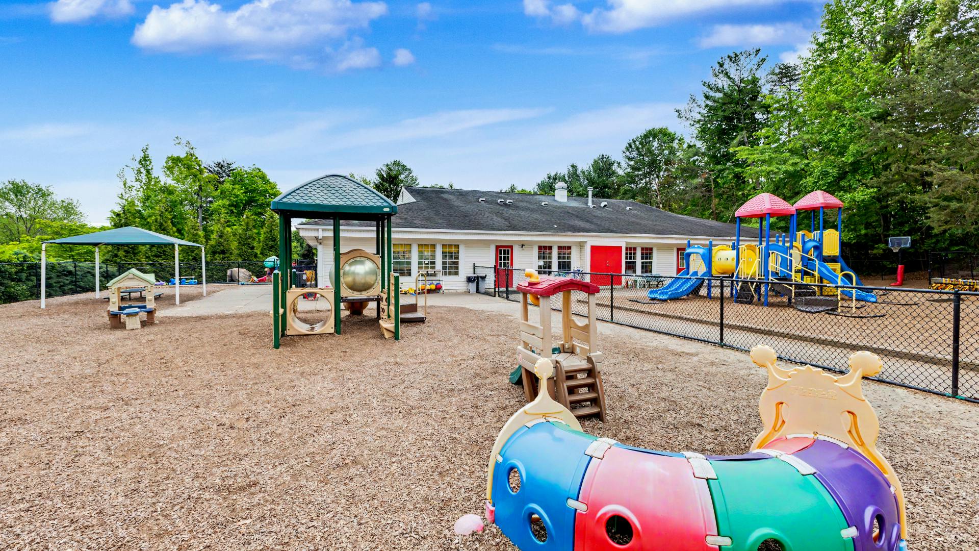 Outdoor playground with various play structures and a building in the background