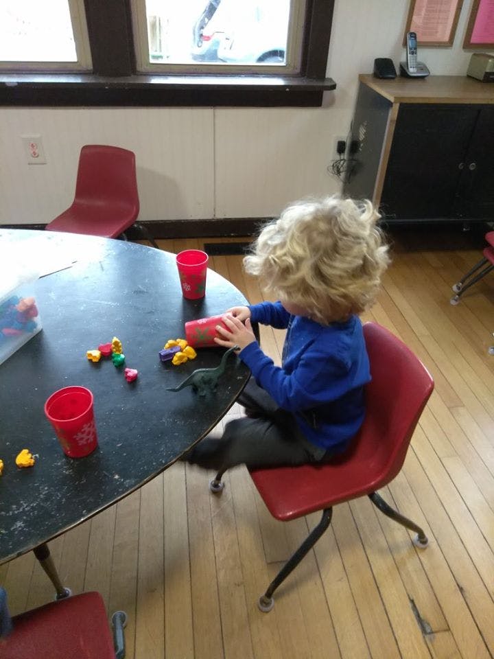 Child with curly hair playing with toys at a table