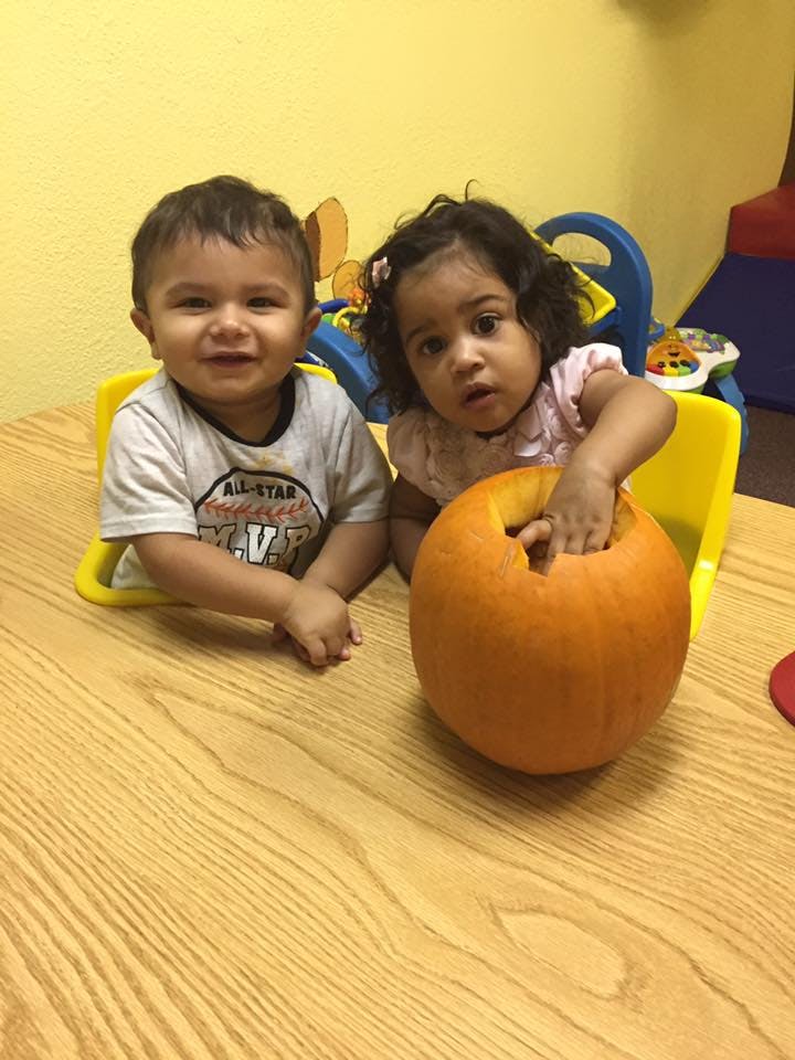 Two children at a table with a pumpkin