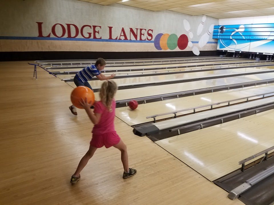 Child bowling with another child in the background
