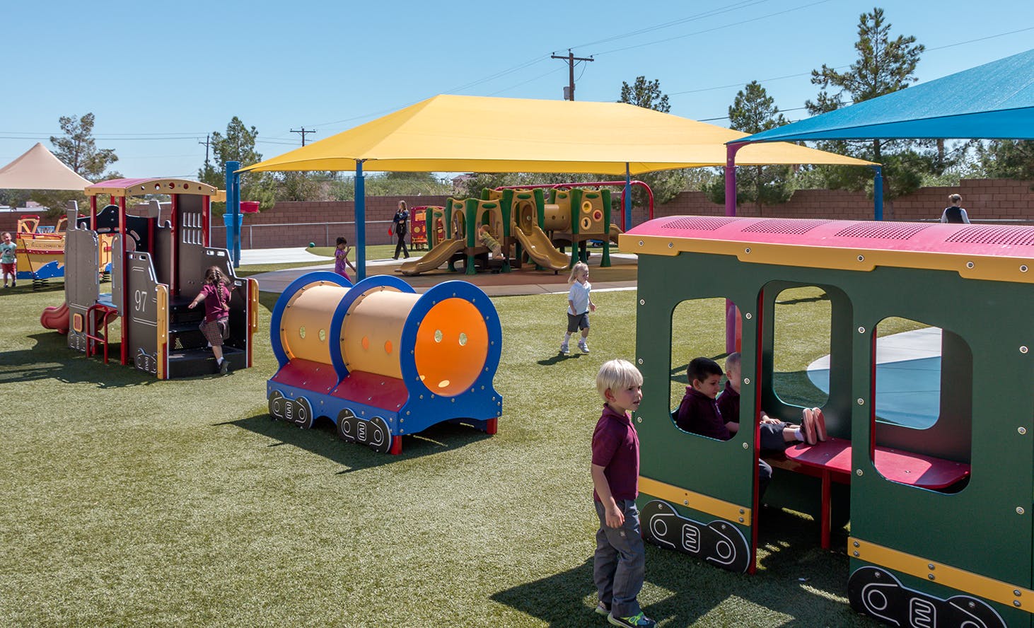 Children playing on a playground with train-shaped play structures