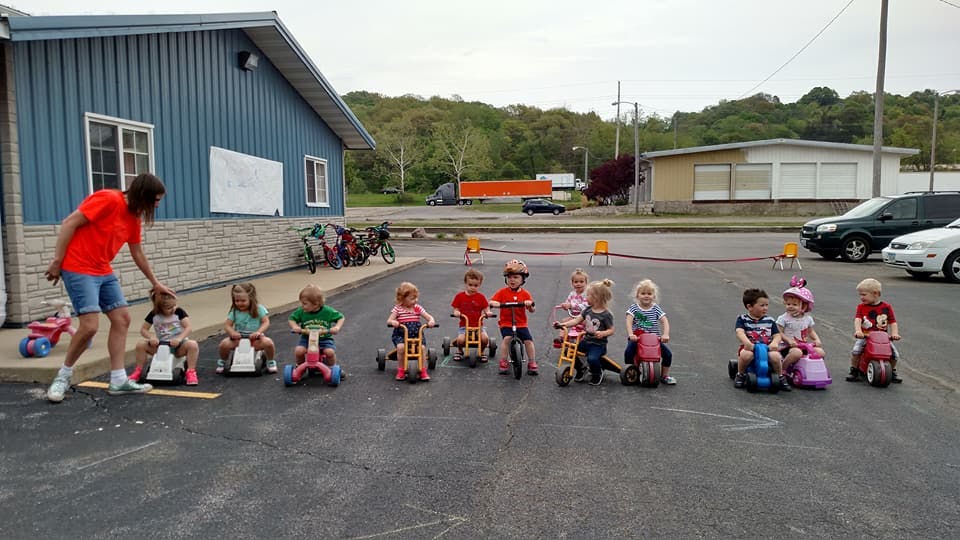Person with children on tricycles in a parking lot
