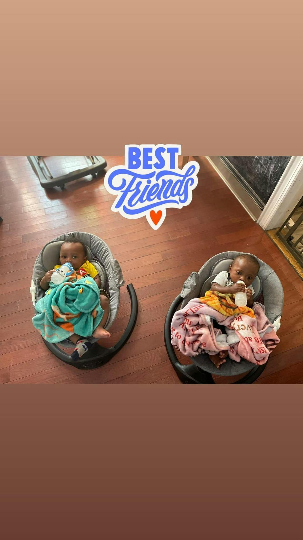 Two babies in bouncers, one holding a bottle