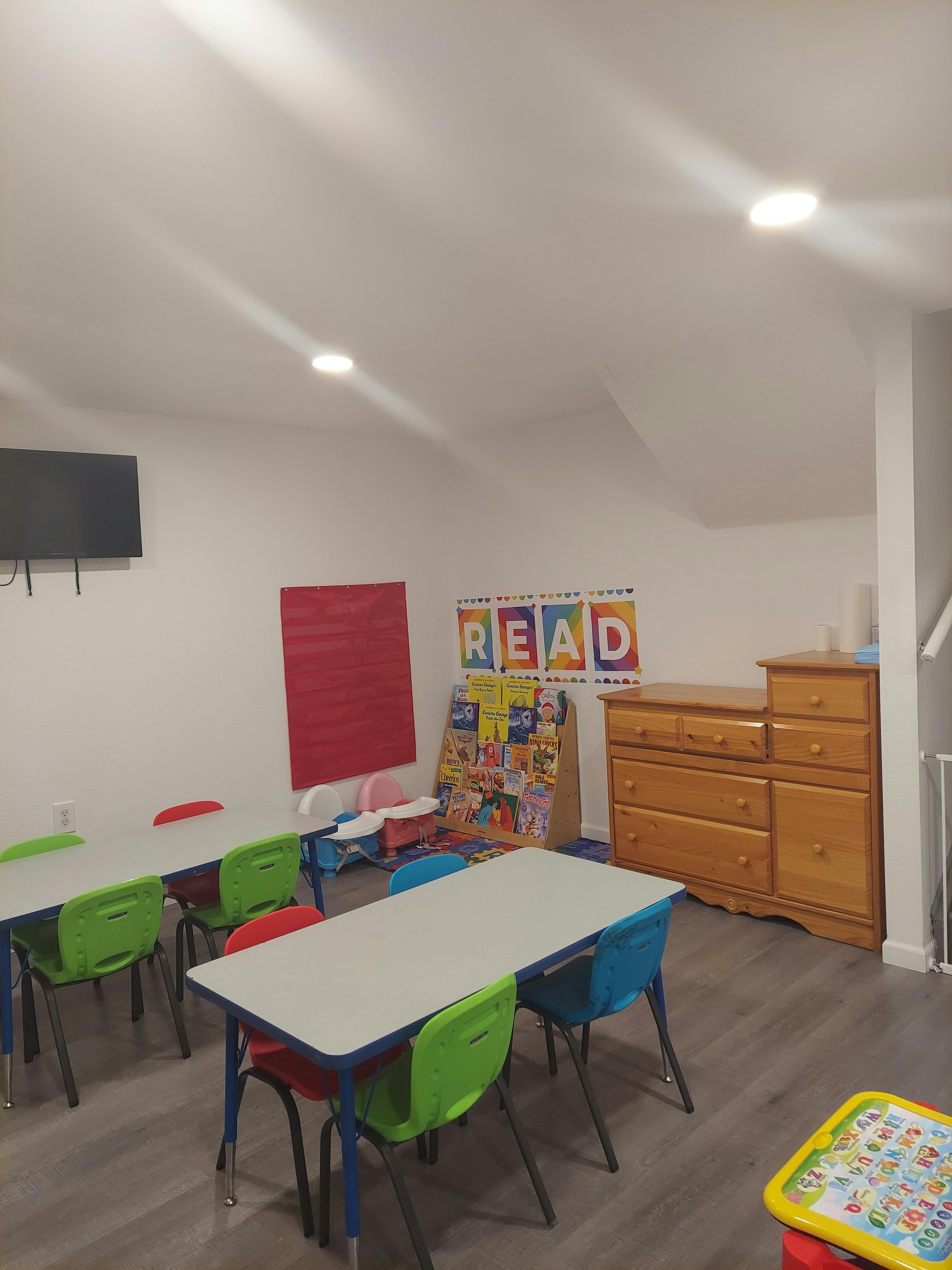 Classroom with small tables and chairs, "READ" sign on wall