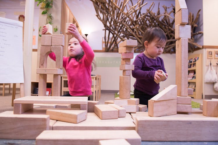 Two children playing with wooden blocks in a classroom